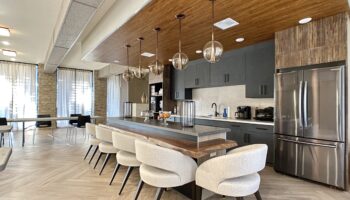 Communal luxury dining room with wood tables, steel appliances and slef service coffee bar