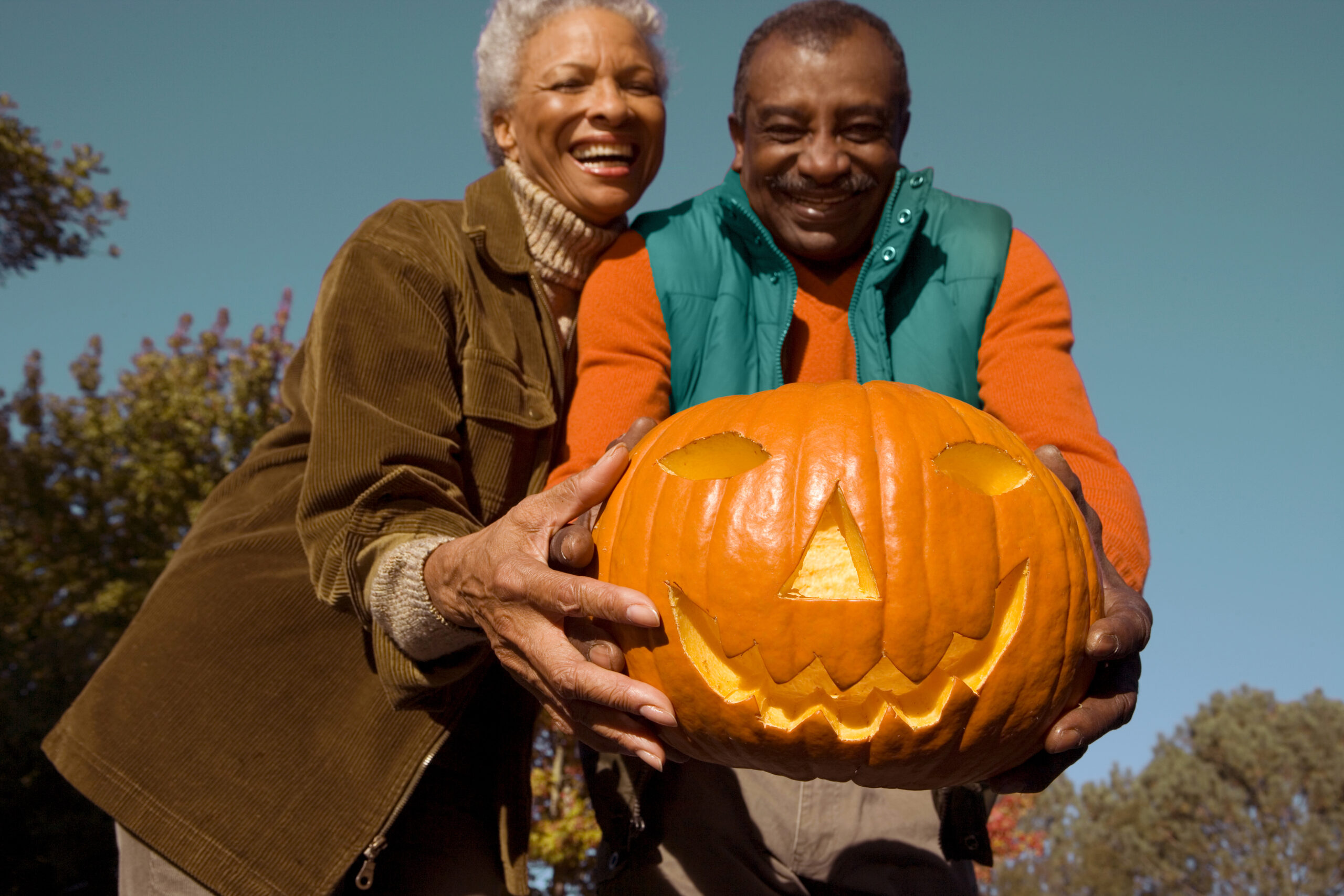 An senior couple holding a Jack O Lantern carved pumpkin