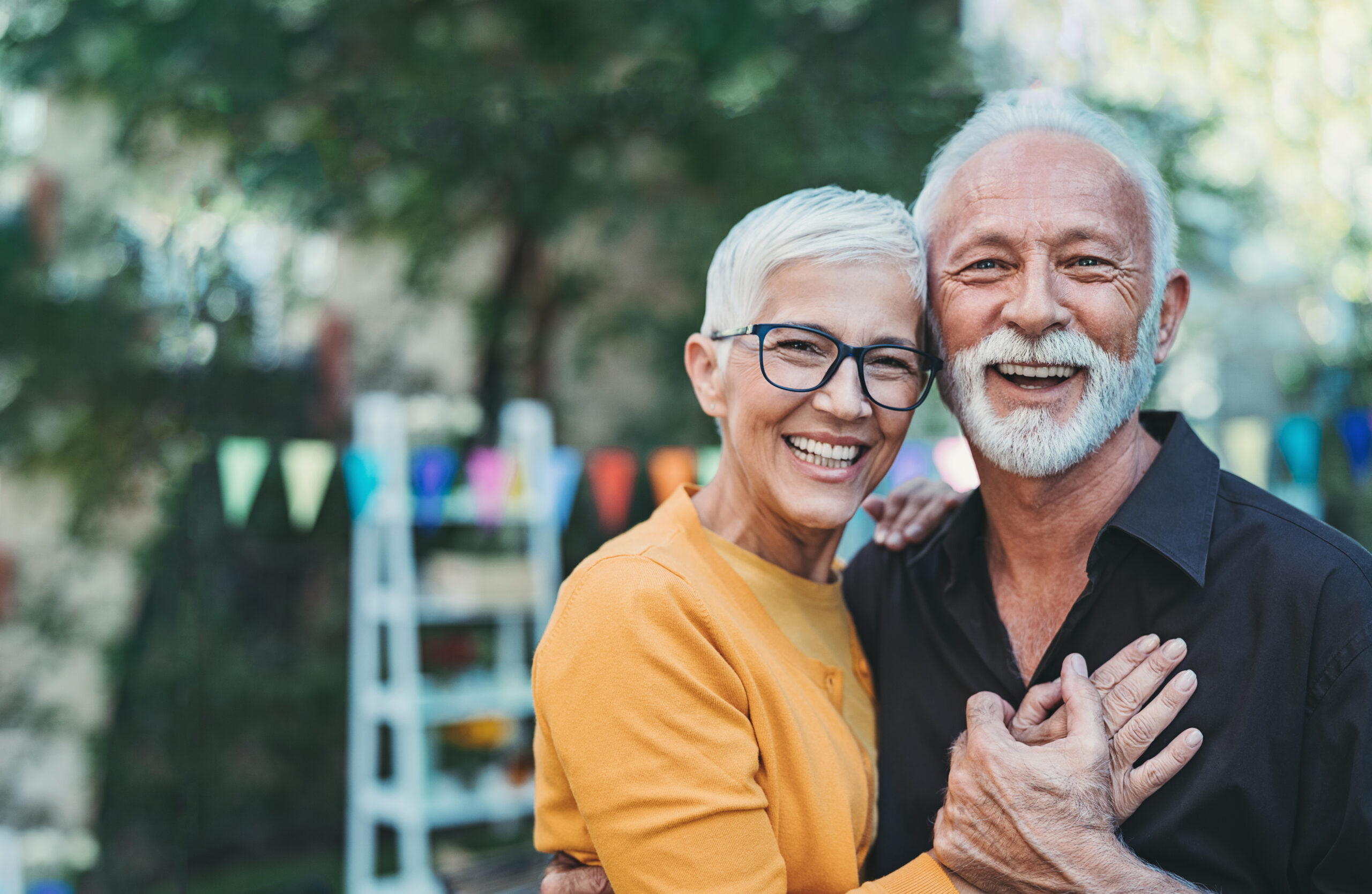 Happy older couple smiling and hugging outdoors with festive decorations in the background in Arizona