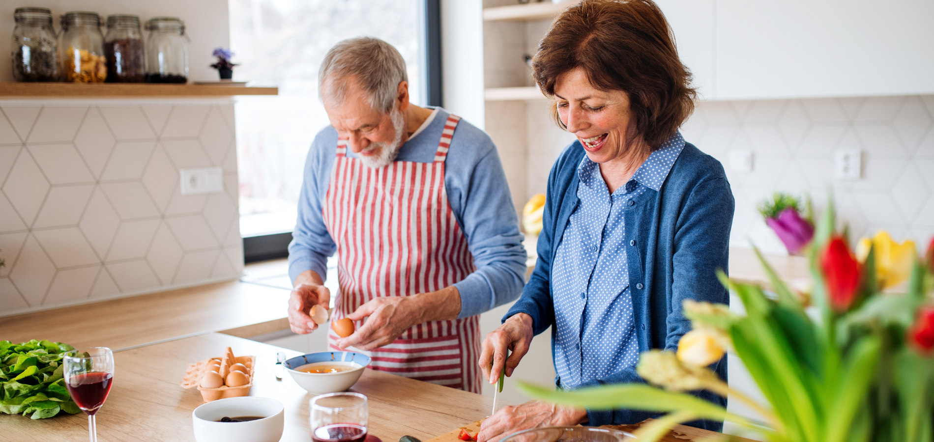 Older couple cooking together in a modern kitchen, smiling and cracking eggs in Arizona