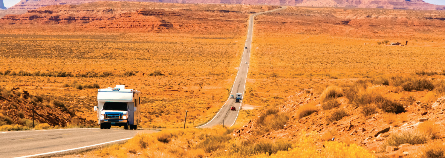 RV driving through a desert highway with Monument Valley rock formations in the distance in Arizona