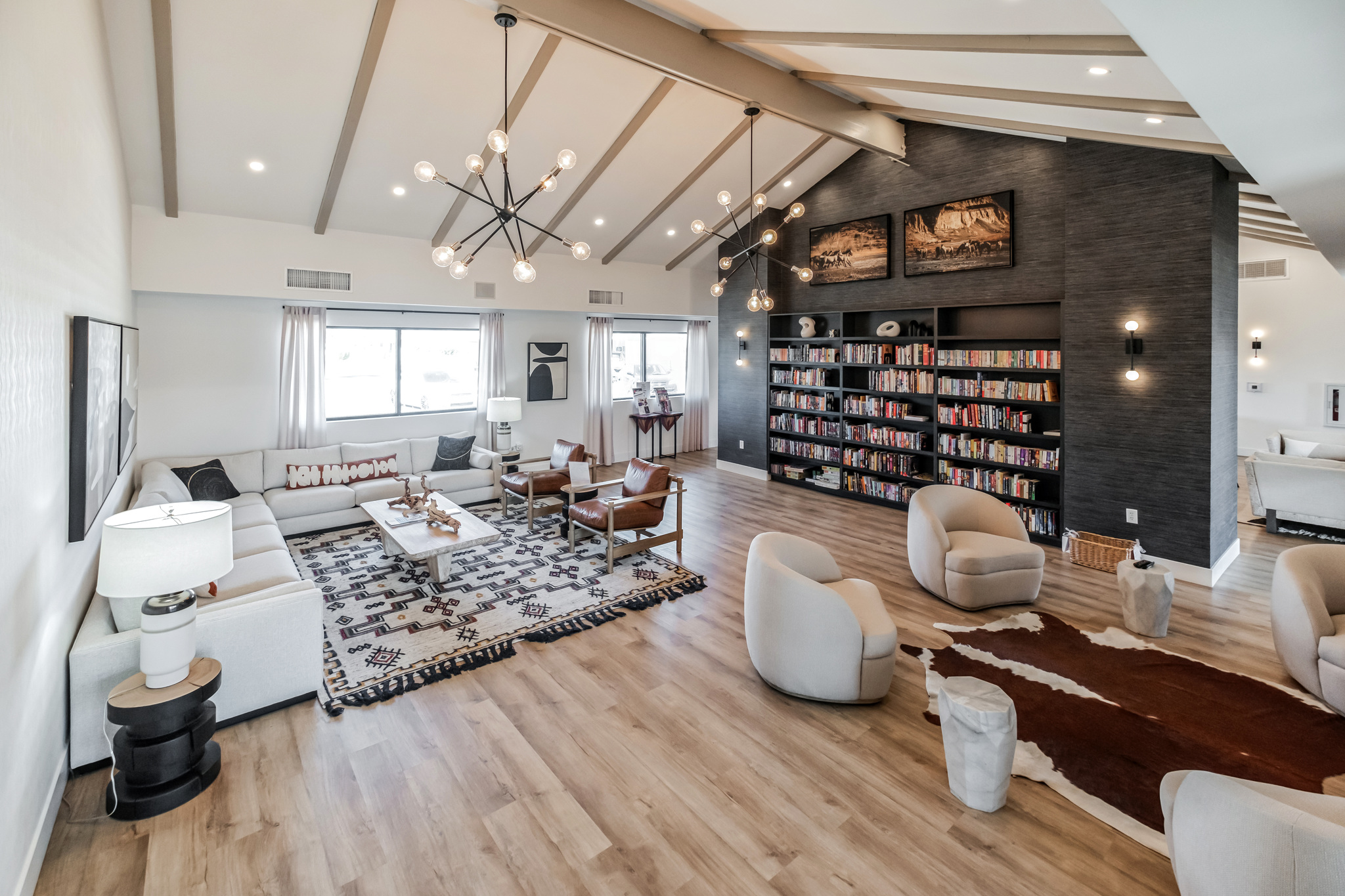 Modern clubhouse lounge with a high ceiling, cozy seating areas, bookshelves, and stylish lighting fixtures in mesa az