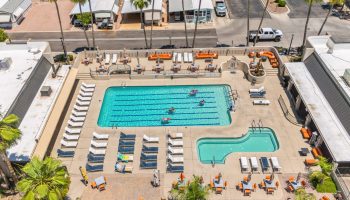 Aerial view of swimming pool area with lounge chairs, hot tub, and people swimming in Arizona